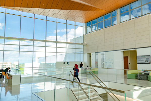 A student walking near a wall of windows in the Bioengineering and Sciences Building.