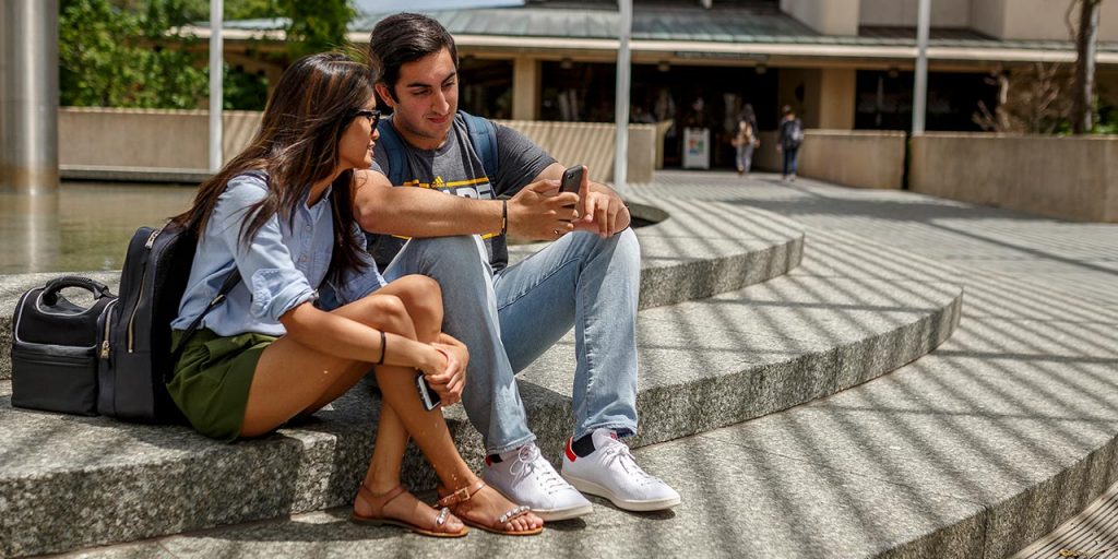 students on campus looking at a phone