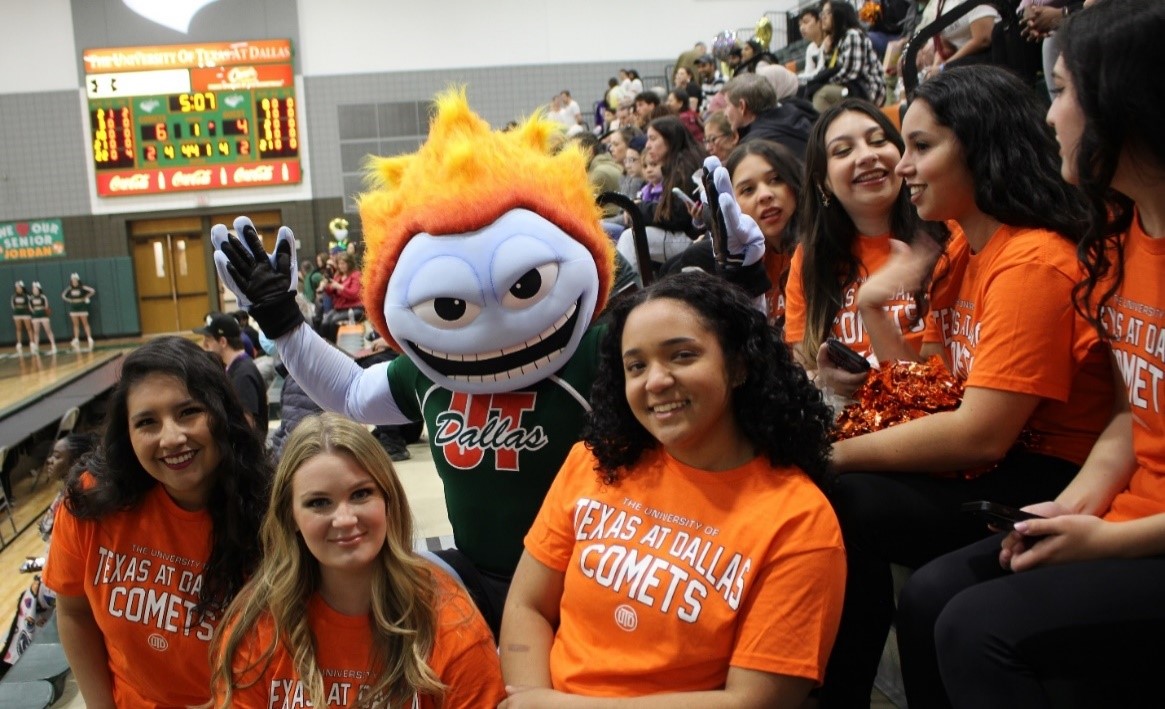 Power Dancers pose with UTD mascot Temoc at a basketball game.